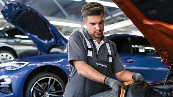 Mechaniker füllt Flüssigkeit in Motor