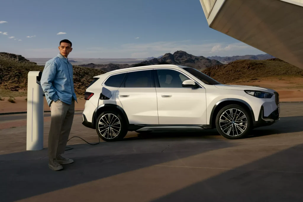 BMW iX1 mit Mann an Ladesäule