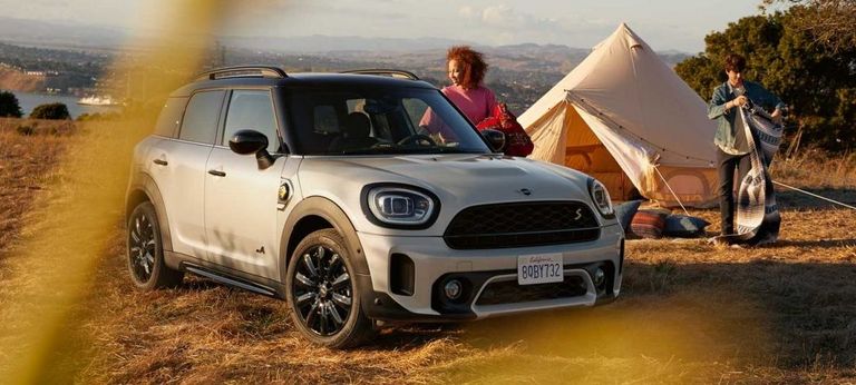 junges Paar neben Mini, daneben ein Camping-Zelt