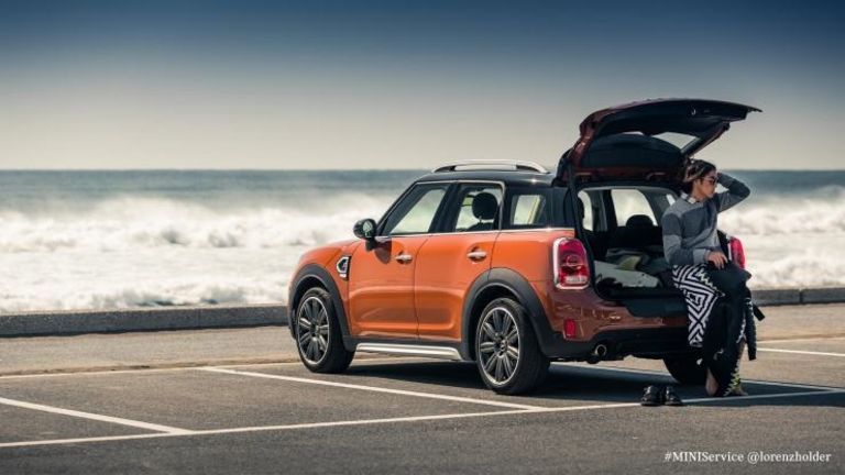 MINI mit geöffneter Kofferraumklappe am Meer mit Mensch davor