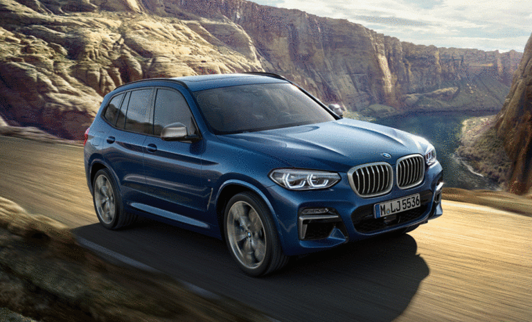 blauer BMW auf Straße in gebirgiger Landschaft