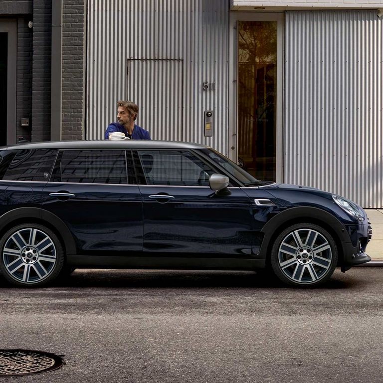 mini_mobilitaetseinschraenkung_ Mann steht an seinem dunklen MINI