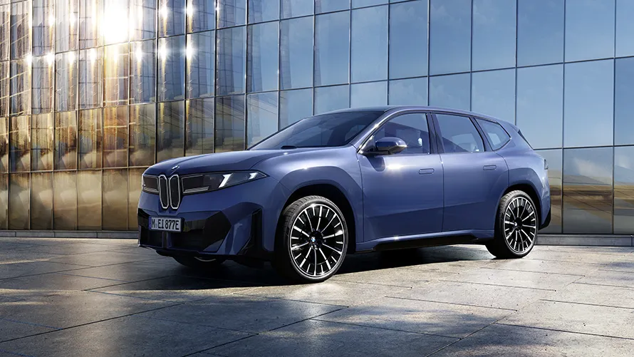 BMW iX3 steht vor spiegelndem Gebäude