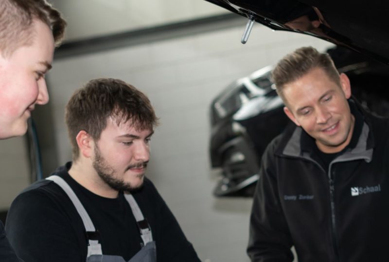 Azubis mit ihrem Meister am Fahrzeug